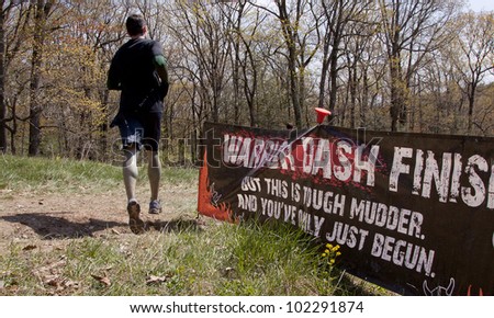 POCONO MANOR, PA - APR 28: A man runs past a sign that reads Warrior Dash Finish at Tough Mudder on April 28, 2012 in Pocono Manor, Pennsylvania. British Royal troops designed the course.