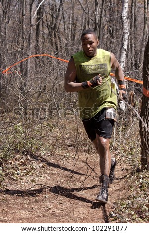 POCONO MANOR, PA - APR 29: A man runs on a trail through the woods at Tough Mudder on April 29, 2012 in Pocono Manor, Pennsylvania. The course is designed by British Royal troops.