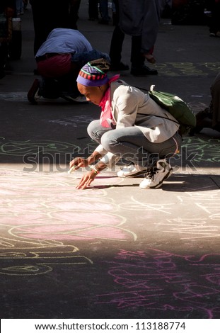 NEW YORK - SEPT 17: A protester writes on the sidewalk in front of Trinity Church with chalk on the 1yr anniversary of the Occupy Wall St protests on September 17, 2012 in New York City, NY.