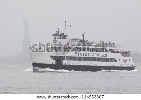 NEW YORK-OCT 9: A Statue Cruise ferry with tourists aboard returns to port in rain and fog with the Statue of Liberty in the background in New York on October 9, 2012.