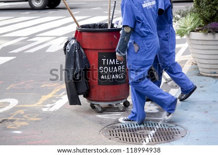 NEW YORK - OCT 18: Two Times Square Alliance workers in blue jumpsuits push a garbage bin as they clean up trash in New York City on October 18, 2012.