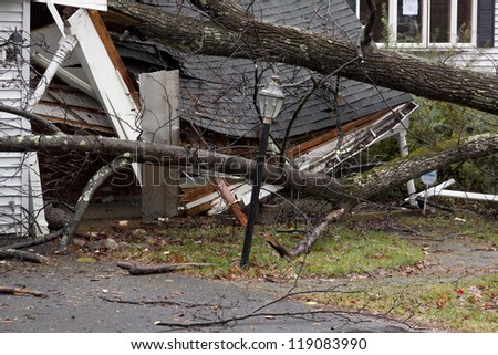 ANDOVER, NJ - OCT 30: A lamppost still standing in front of a tree laying across the front porch of a home after Hurricane Sandy made landfall in the US in Andover, New Jersey on October 30, 2012.