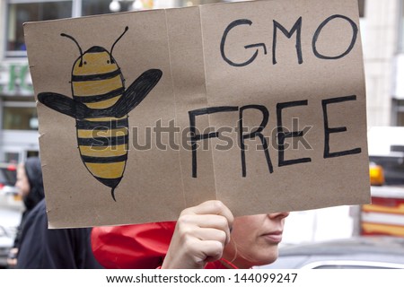 A close up of a sign that reads GMO Free with a drawing of a bee during a march against genetically modified organisms, also known as GMO\'s.