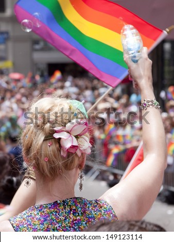 NEW YORK-JUN 30: A woman with flowers in her hair waves a rainbow flag and blows bubbles from a toy bubble gun at the 44th Annual NYC Pride March down 5th Avenue on June 30, 2013 in Manhattan.