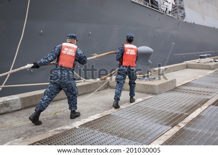 STATEN ISLAND, NY - MAY 21, 2014: Sailors from NWS Earle Port Services tend the lines of the guided-missile destroyer USS Cole (DDG 067) as the ship docks at Sullivans Piers for Fleet Week NY.