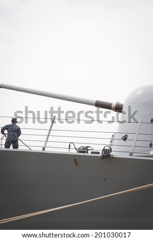 STATEN ISLAND, NY - MAY 21, 2014: A sailor on the guided-missile destroyer USS Cole (DDG 067) standing near the MK45 5 inch gun tends the lines as the ship docks at Sullivans Piers during Fleet Week NY.