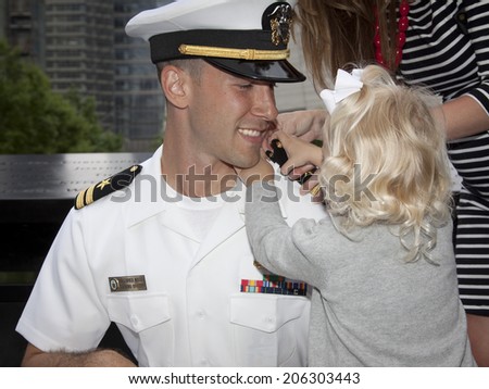 NEW YORK - MAY 23, 2014: US Navy Lt. Christopher Mikell\'s daughter fastens new shoulder boards to his uniform during his promotion ceremony at the National September 11 Memorial site.