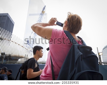 NEW YORK - SEPT 11, 2014: A tourist takes a picture of the Freedom Tower and structures at the WTC site on the anniversary of the 2001 September 11 terrorist attacks in Lower Manhattan.