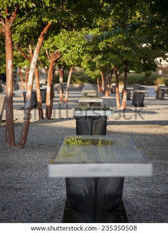 ARLINGTON, VA - SEPT 13, 2014: A line of granite and stainless steel memorial units among Crape Myrtle trees at the Pentagon Memorial. The benches have the name of each victim of the 2001 attack.