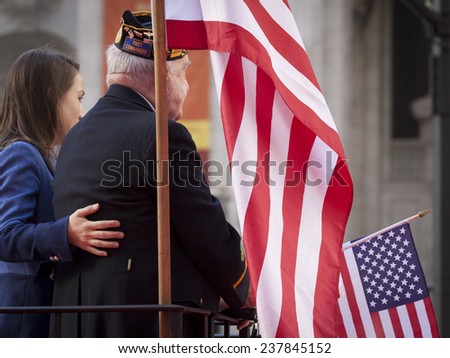 NEW YORK - NOV 11, 2014: An older US vet on a parade float holds an American Flag in the 2014 America\'s Parade held on Veterans Day in New York City on November 11, 2014.