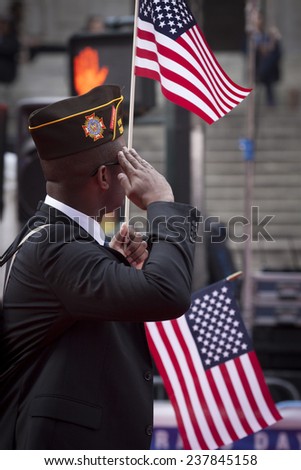 NEW YORK - NOV 11, 2014: A vet carrying an American Flag salutes as he marches past the VIP stage during the 2014 America\'s Parade held on Veterans Day in New York City on November 11, 2014.