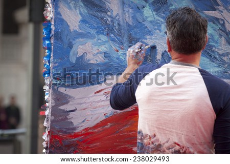NEW YORK - NOV 11, 2014: American artist Scott LoBaido paints an American Flag on a large canvas in real time during the 2014 America's Parade on Veterans Day in New York City on November 11, 2014.