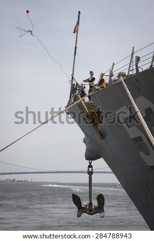 STATEN ISLAND, NY - MAY 20 2015: Linesmen work on the bow of USS Barry (DDG 52) guided-missile destroyer mooring for Fleet Week NY at Sullivans Pier with the Verrazano-Narrows Bridge in background.