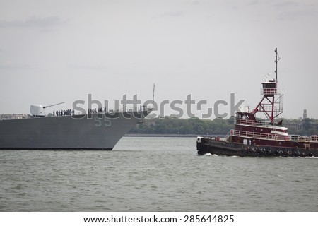 STATEN ISLAND, NY - MAY 20, 2015: The bow of the USS Stout (DDG 55) and the McAllister Sisters tugboat as the warship is guided into port at Sullivans Pier in Staten Island at the start of Fleet Week.