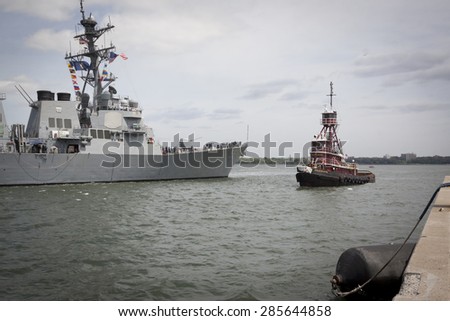 STATEN ISLAND, NY - MAY 20, 2015: USS Stout (DDG 55) is guided into port by a McAllister tugboat at Sullivans Pier in Staten Island after the Parade of Ships at the start of Fleet Week.