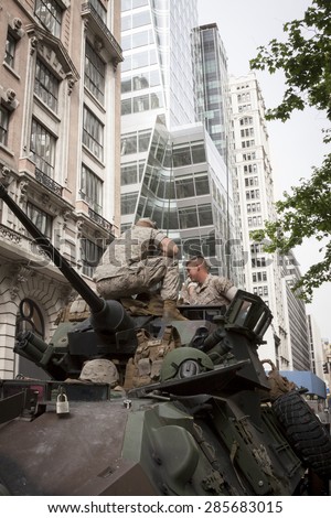 NEW YORK - MAY 21 2015: Two US Marines sit on top of a military tank parked on the street during a demonstration for the public at Bryant Park for Marine Day during Fleet Week NY.