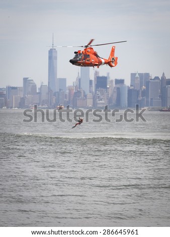 STATEN ISLAND, NY - MAY 24 2015: A Coast Guard rescue swimmer is hoisted line into a US Coast Guard MH-65 Dolphin helicopter for a Search and Rescue demonstration at Sullivans Pier during Fleet Week.