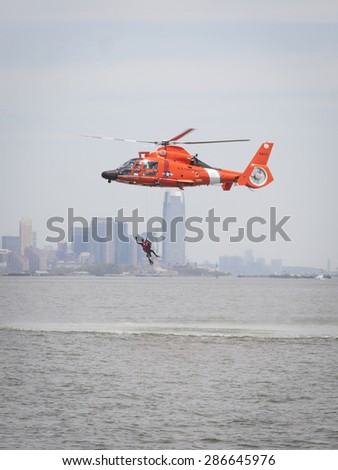 STATEN ISLAND, NY - MAY 24 2015: A Coast Guard rescue swimmer waves when hoisted by line into a US Coast Guard MH-65 Dolphin helicopter for a Search and Rescue demonstration for Fleet Week 2015.