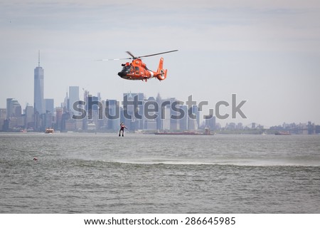 STATEN ISLAND, NY - MAY 24 2015: A Coast Guard rescue swimmer is hoisted by line from the water into a US Coast Guard MH-65 Dolphin helicopter for a Search and Rescue demonstration during Fleet Week.