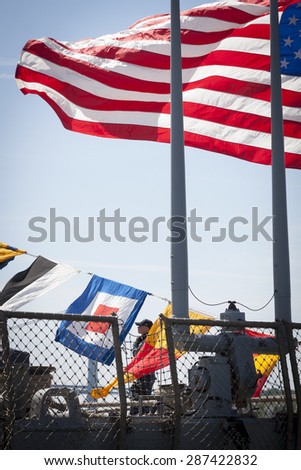 STATEN ISLAND, NY - MAY 24 2015: Armed security personnel standing under the American flag flying from the stern of guided-missile destroyer USS Barry (DDG 52) at Sullivans Pier during Fleet Week NY.