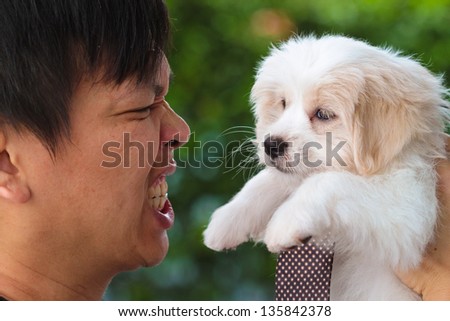 Man making angry face at cute maltese puppy.