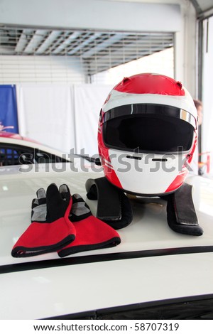 Racing helmet and glove on race car roof. Concept of  personal safety.
