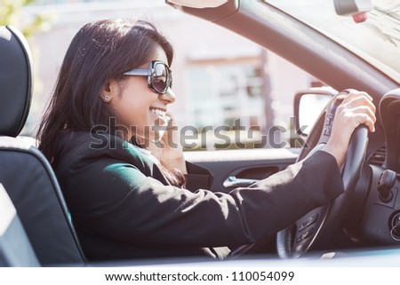A shot of an Indian businesswoman driving a car and talking on the phone