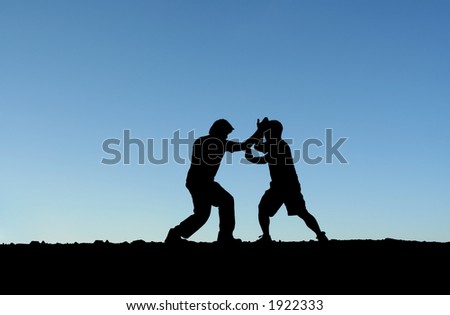 Two men practicing martial arts on top of a mountain (in silhouette)