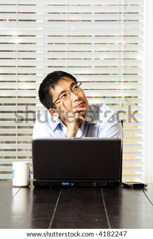 An asian businessman thinking and working on his laptop