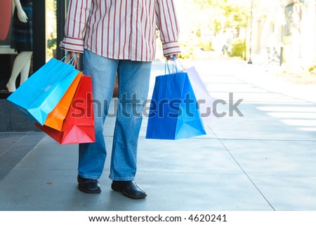 A young man carrying shopping bags at an outdoor shopping mall