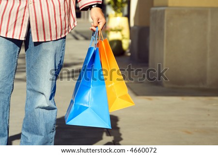 A young man carrying shopping bags at an outdoor mall