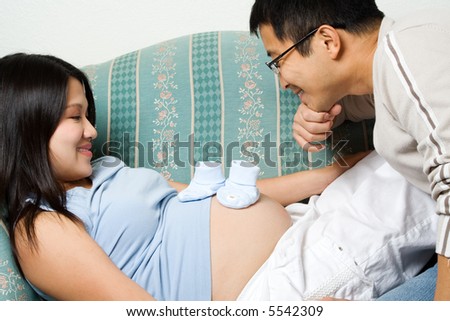 A shot of a father and mother looking at her unborn baby's shoes