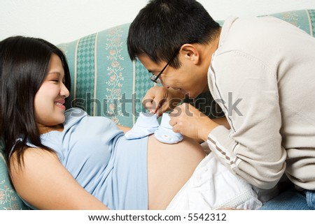 A shot of a father and mother playing with her unborn baby\'s shoes