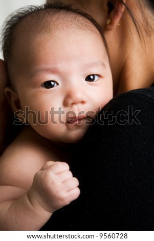 stock photo A portrait of a cute asian baby boy in his mother's arm