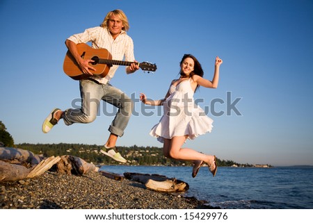 A shot of a young caucasian couple jumping for joy on the beach