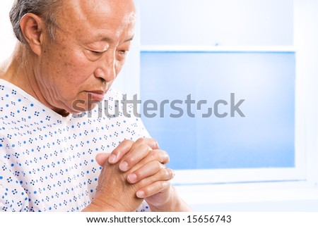 A shot of a senior asian man praying in hospital