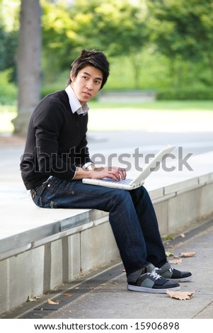 An asian student working on his laptop at the campus