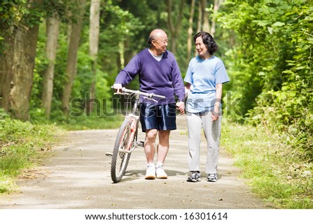 A couple senior asian talking while walking and exercising at a park