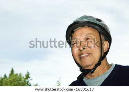 A shot of an elderly asian man wearing a bike helmet