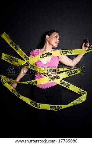 A businesswoman trapped in yellow caution tape trying to talk on her cellphone