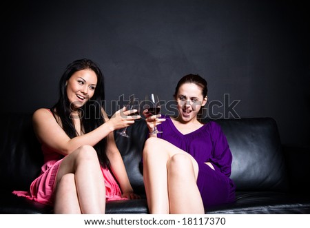 Two happy beautiful women toasting wines during a party in a club