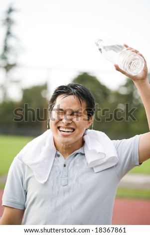 A young active sporty Asian male cooling down by pouring water on top of his head after exercise