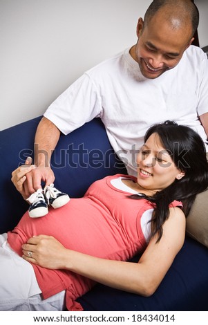 A shot of a father and mother playing with her unborn baby\'s shoes