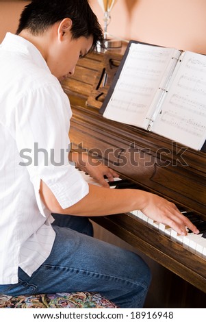 A shot of an asian man playing piano