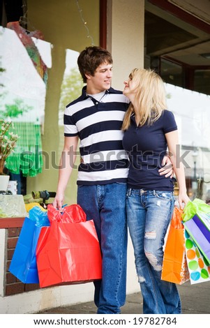 A caucasian couple carrying shopping bags walking in an outdoor mall
