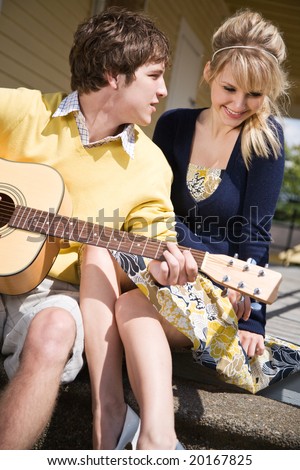 A young caucasian man playing guitar and sings to his girlfriend