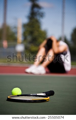 A sad male tennis player sitting down in disappointment after defeat
