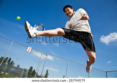  photo : An asian tennis player jumping in the air hitting a tennis ball