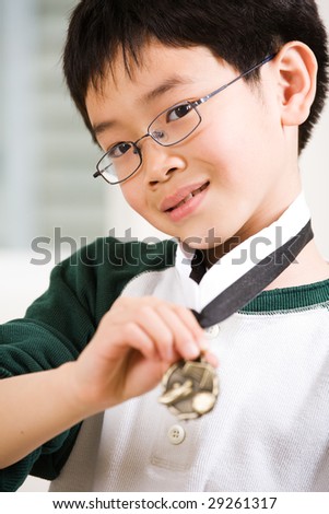 An asian boy showing his winning sport medal