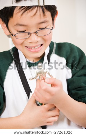 An asian boy looking at his winning sport medal and trophy
